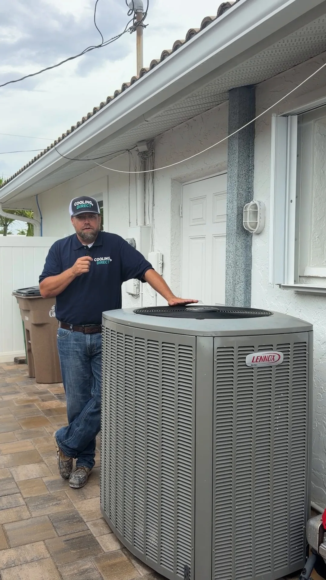 A Cooling Direct team member standing beside an outdoor AC unit at a Southwest Florida home